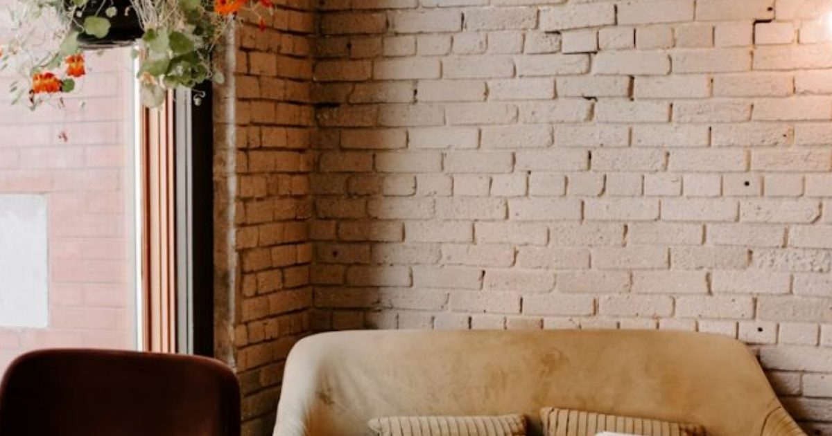 Painted brick wall beside a window, with a cream sofa and a brown armchair
