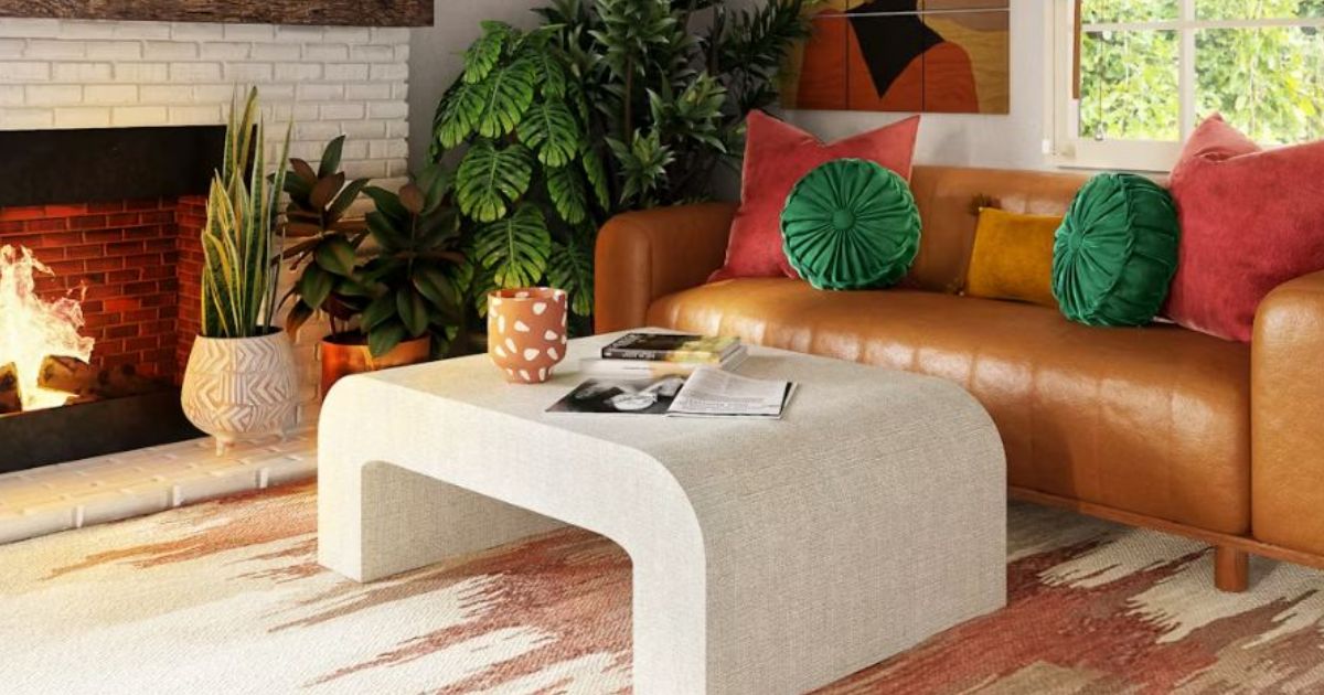 Tan leather sofa with green cushions, a plant and a fireplace in a living room