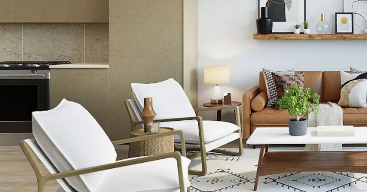 White armchairs facing a tan leather sofa and coffee table, with a kitchen behind