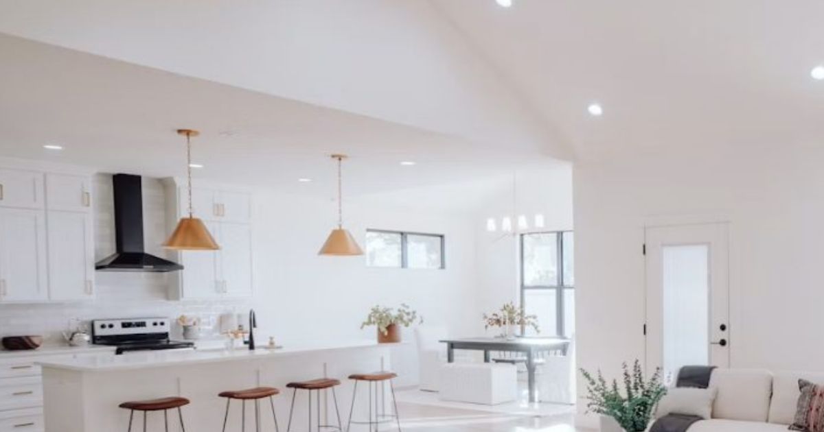 Bright open-plan kitchen with white cabinets and pendant lights