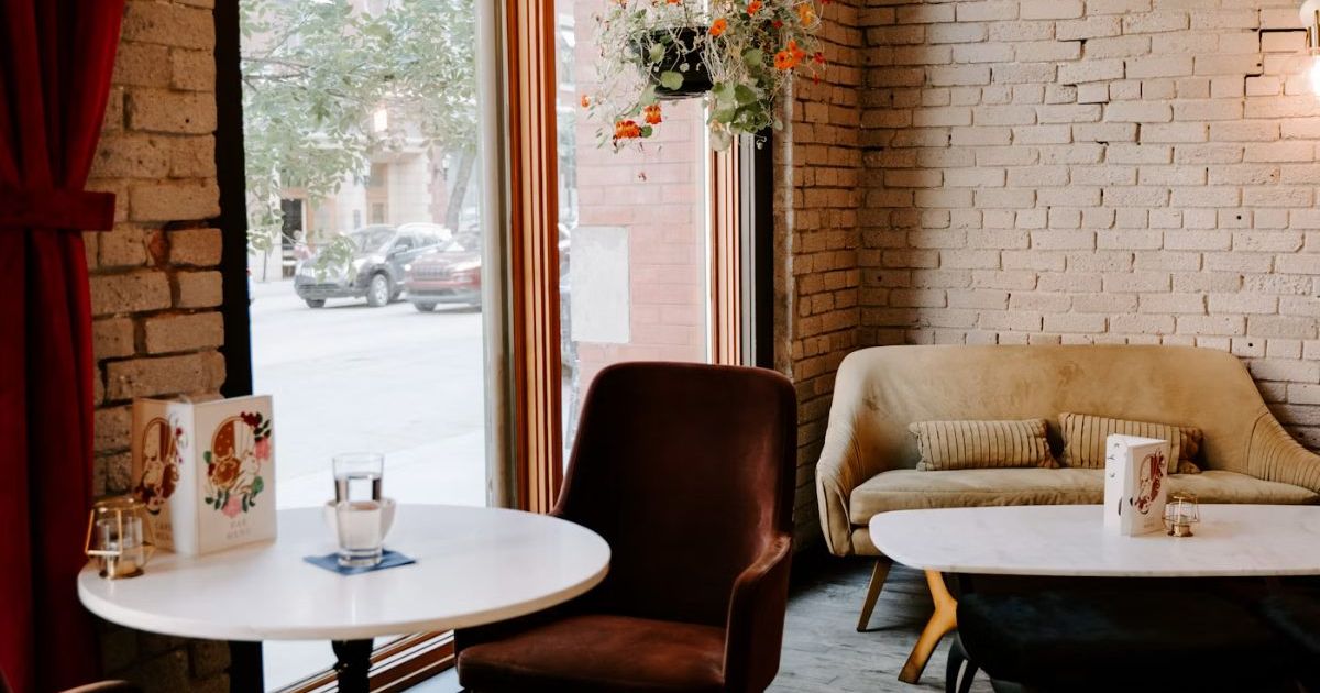Café-style corner with a brick wall, a round table and a leather armchair by a window